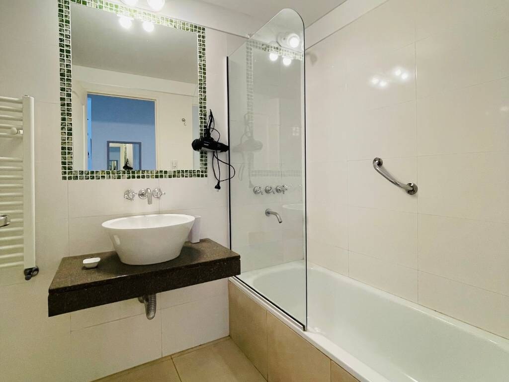 Bathroom with vessel sink, mirror and bathtub with glass screen