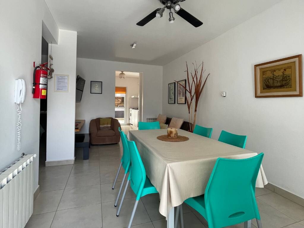 Table with turquoise chairs, armchair and ceiling fan