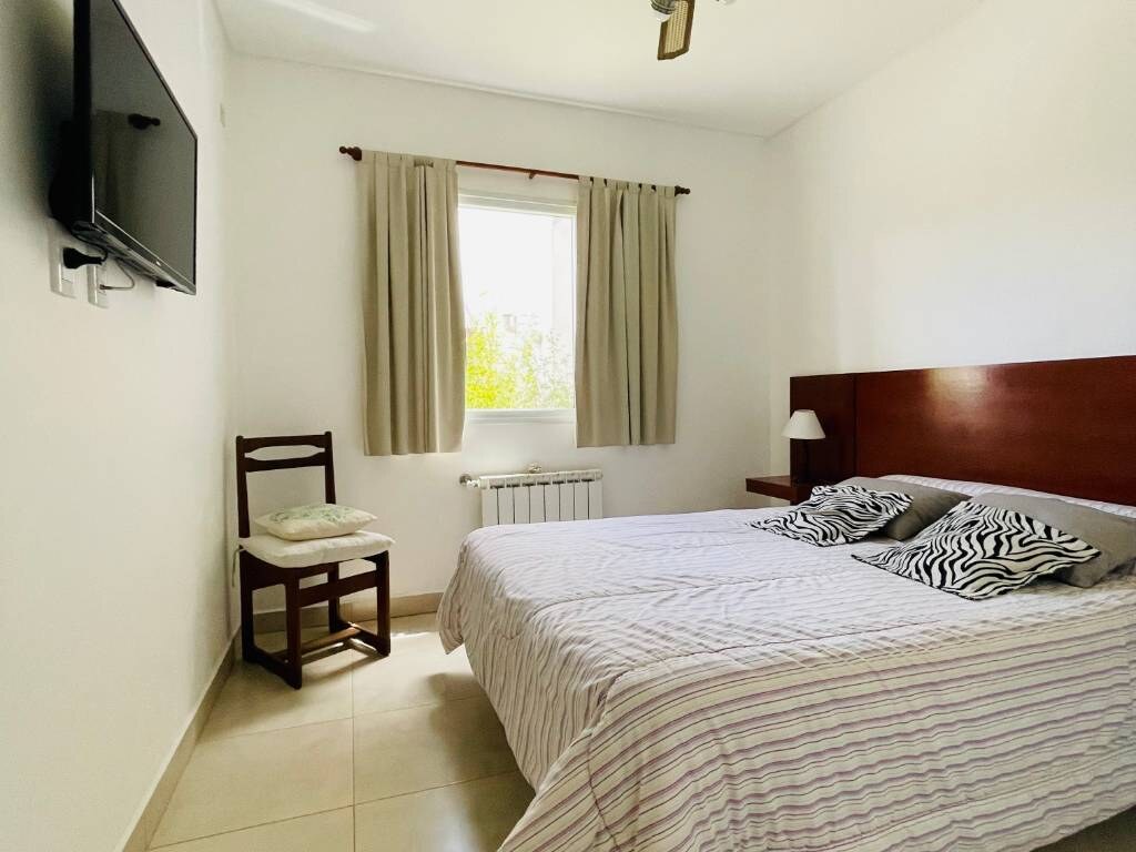 Double bed with wooden headboard and wall-mounted TV