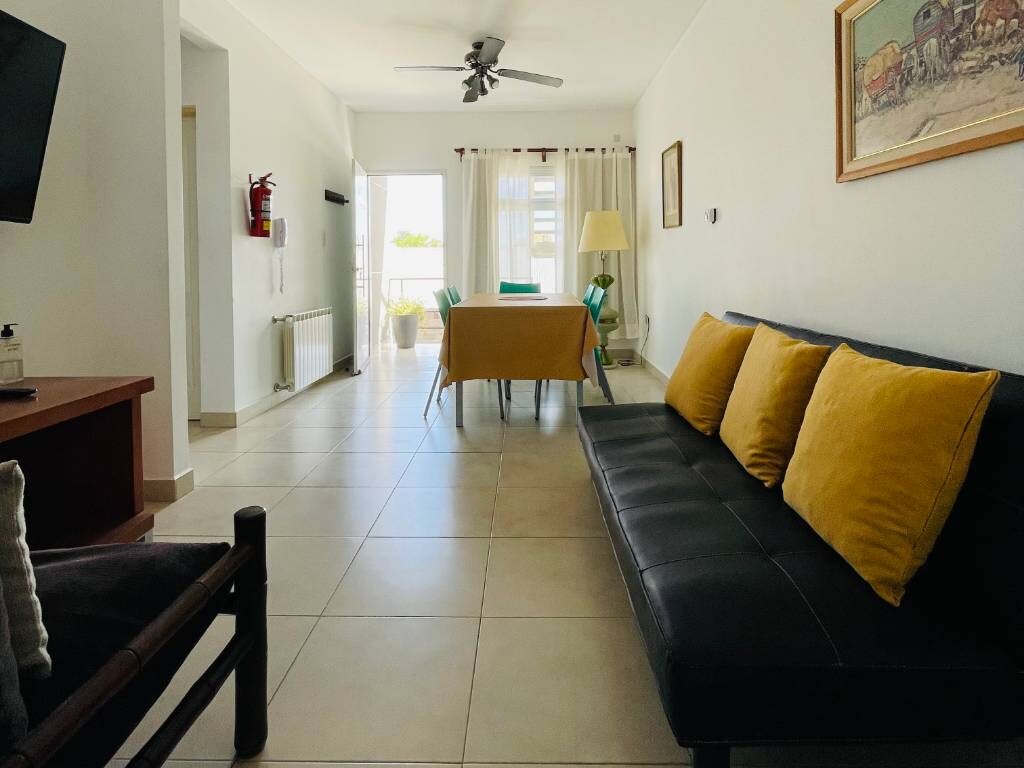 Black sofa with yellow cushions and table in the background