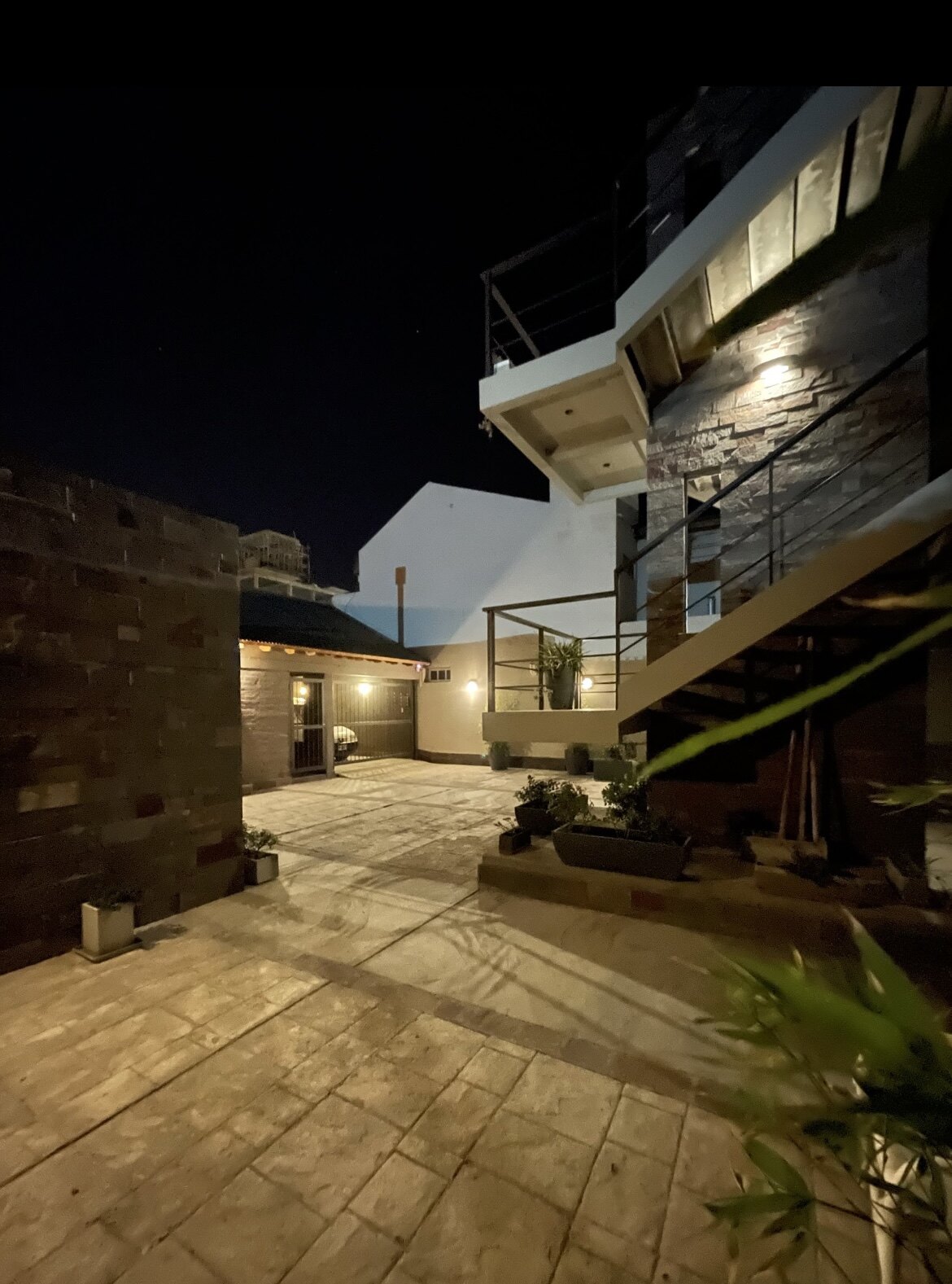 Patio lit up at night with plants and staircase